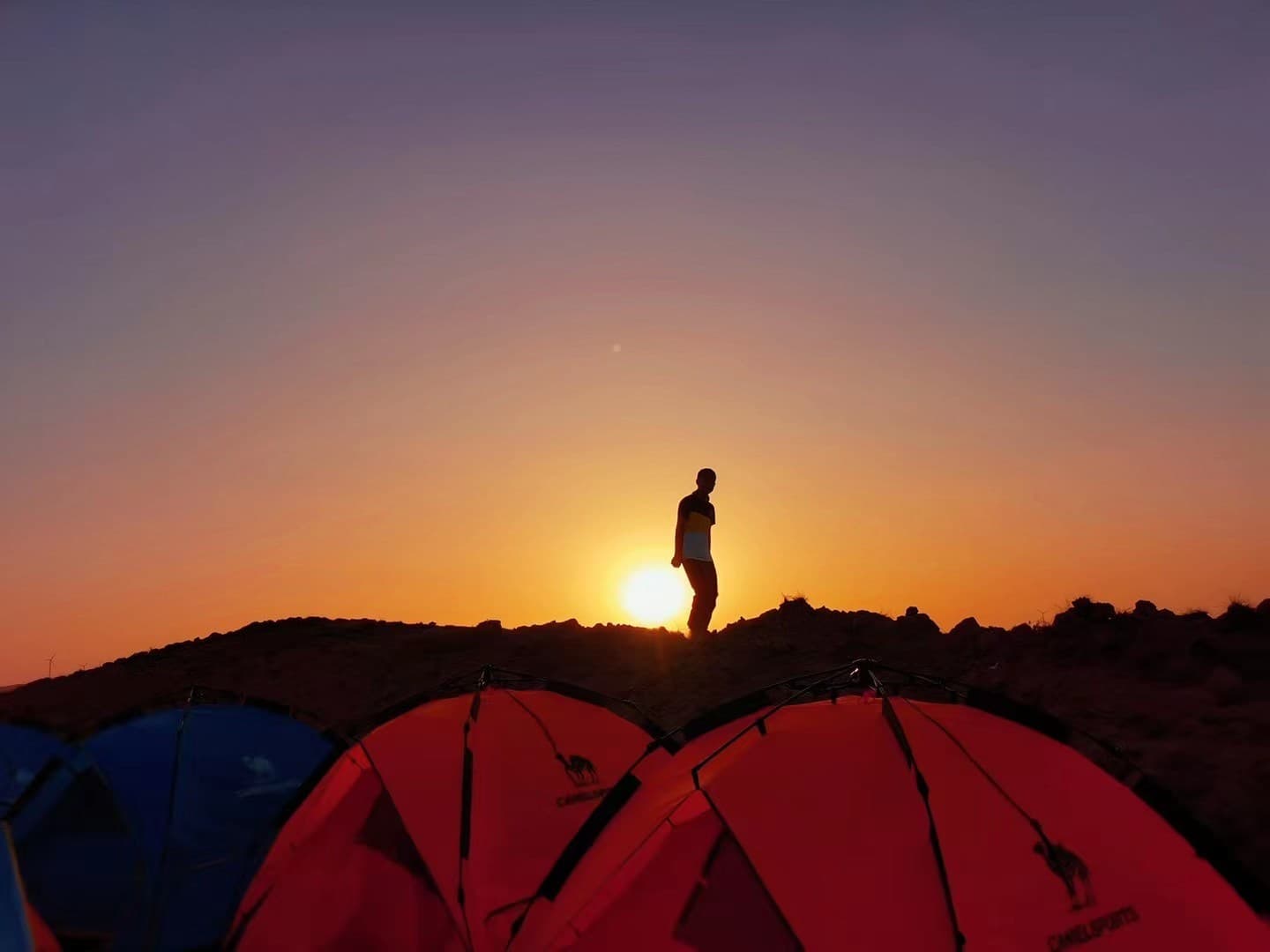 宁夏中卫沙漠日出时的营地帐篷和人物剪影
